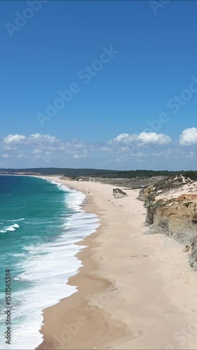 High drone view of Caparica beach near Lisbon, Portugal. Vehicle tracks drawn in the sand meet soft Atlantic waves. Aerial shot showing natural patterns and contrast between land and sea.
