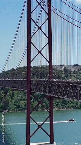 Urban drone flight under the iconic 25 de Abril Bridge in Lisbon, Portugal. Aerial scene capturing the structure’s scale, water reflections, and vibrant city energy from a dynamic, low-angle view.

