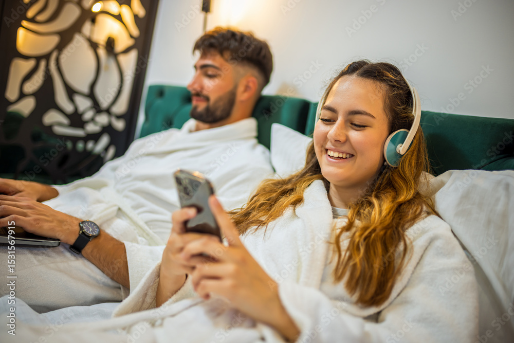 Fototapeta premium Modern Couple in Bed – Separate Digital Worlds, Shared Space