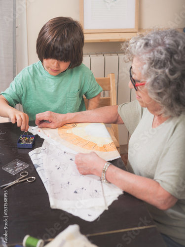 Grandmother and grandson preparing fabrics to sew a cushion together at home