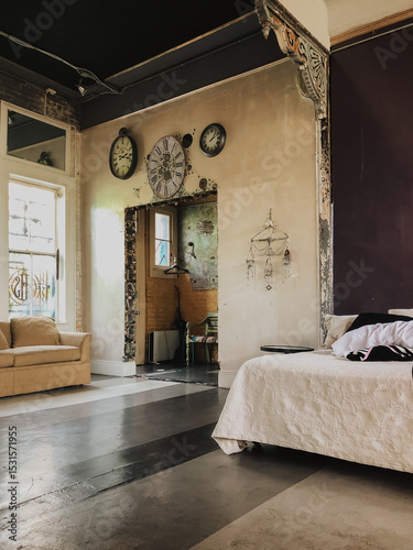 Eclectic vintage bedroom with exposed brick, large wall clocks, worn textures, and layered decor, showcasing rustic charm and bohemian style in an artist loft or creative studio interior