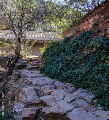 photo of rocky path along a creek bank in AZ with a vintage bridge in the background and ivy growing on the creek bank