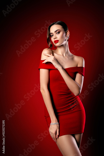 Luxurious elegant young woman in a red dress posing with refined confidence, showcasing beauty, style