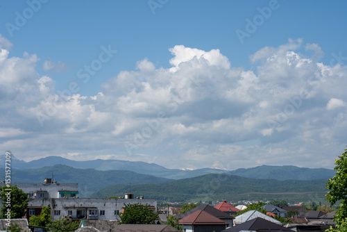 Scenic view of mountains and clouds under blue sky in a quiet town during the day
