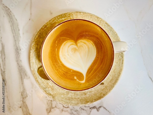 Overhead view of a latte coffee with heart shape latte art on a marble table