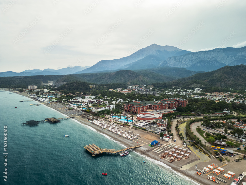 Obraz premium Aerial view of Kemer beach with turquoise Mediterranean sea, crystal clear water and Taurus mountains in the background, Antalya, Turkey