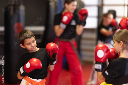 Children kick and punch each other during kickboxing training fight. Students of wrestling tussle class are engaged in gym and are trained in wrestle techniques.