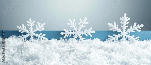 Three white snowflakes stand in artificial snow against a light blue background