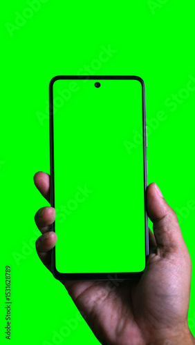 Hand holding smartphone with chroma green screen. Green background