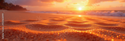 A serene beach scene with golden sand sparkling in the warm light of the setting sun over the ocean.