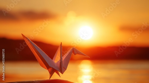 Origami crane at sunset over water.