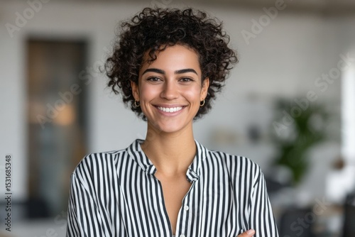 Smiling young african female in striped shirt with curly hair indoors
