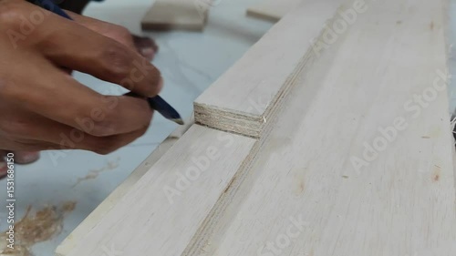 Close-up video of a carpenter's hand marking a mortise joint on a piece of plywood using a blue carpenter's pencil. This footage highlights precision marking in woodworking and the detailed preparatio