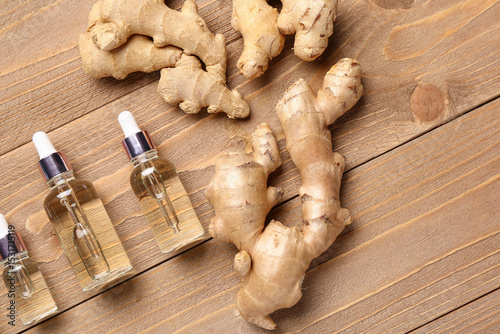 Fototapeta Naklejka Na Ścianę i Meble -  Bottles of ginger cosmetic oil on wooden background