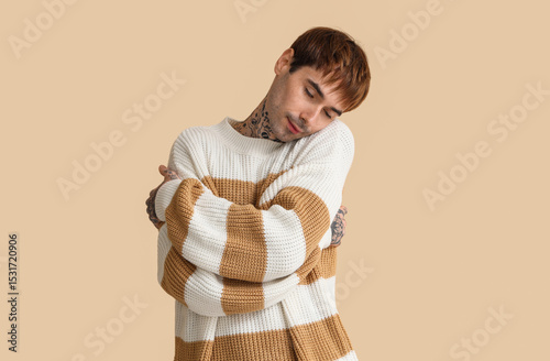 Young man hugging himself o...