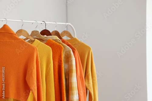 Rack with autumn clothes in light room, closeup