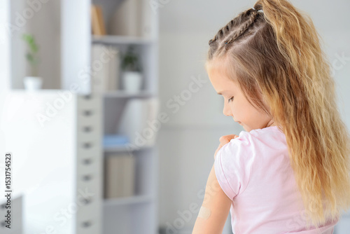 Little girl with applied patch after vaccination in clinic, back view