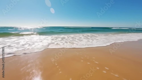 Tranquil beach waves rolling onto soft golden sand under sunlight