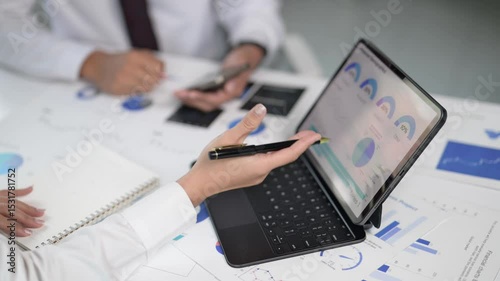 Two people are working on a laptop and a notebook