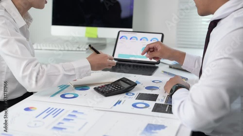 Two people are sitting at a desk with a laptop and a calculator
