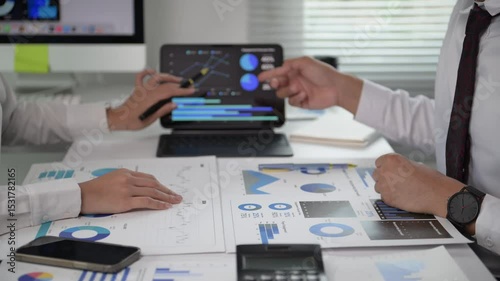Two people are sitting at a desk with a laptop and a tablet