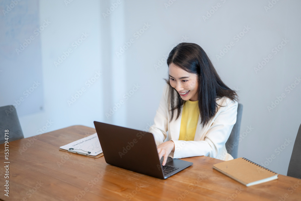 A woman is sitting at a desk with a laptop and a notebook A woman is sitting at a desk with a laptop and a notebook