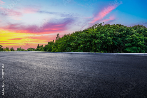 Empty asphalt road and green forest with beautiful sky clouds at sunset