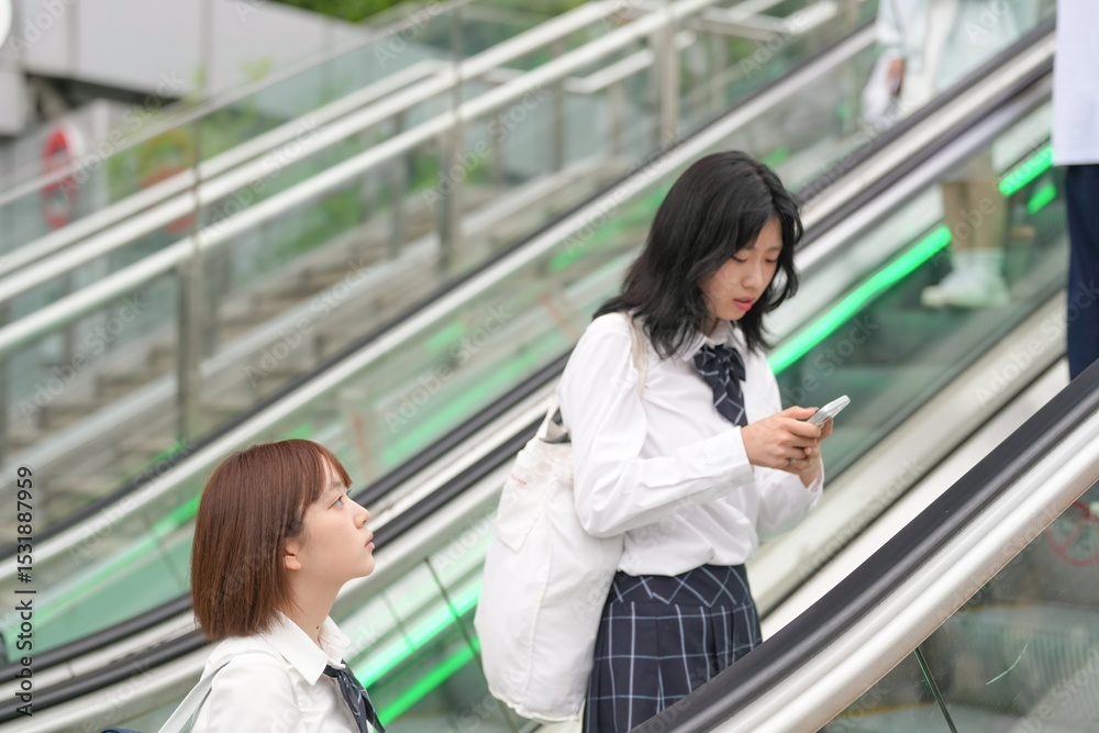 In early summer in Shanghai, near The Bund, Japanese high school girls in uniforms ride an escalator, their matching uniforms and quiet chatter adding youthful energy to the vibrant urban atmosphere. In early summer in Shanghai, near The Bund, Japanese high school girls in uniforms ride an escalator, their matching uniforms and quiet chatter adding youthful energy to the vibrant urban atmosphere.