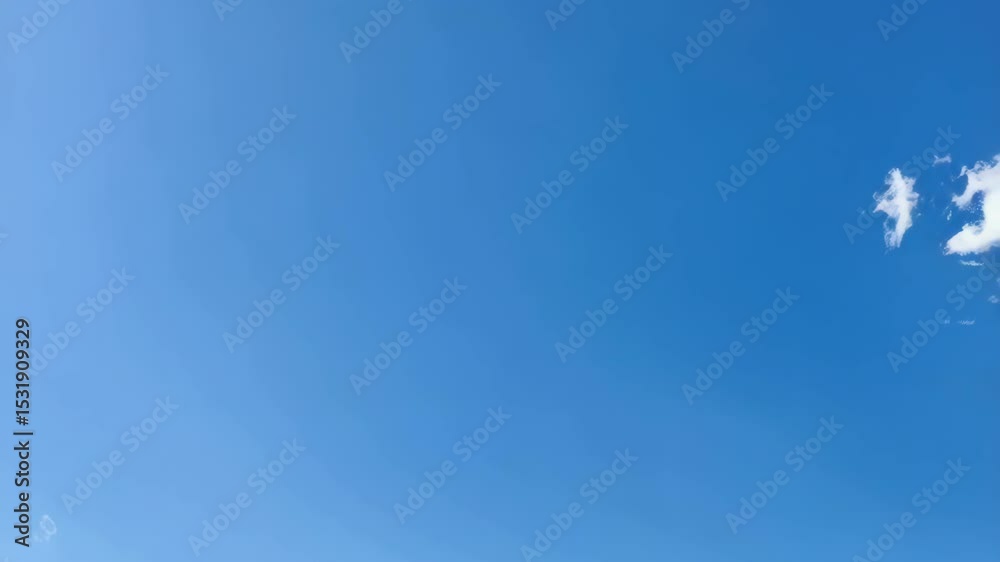 Fluffy white cumulus clouds drifting across a vibrant blue summer sky during the daytime with ample negative space