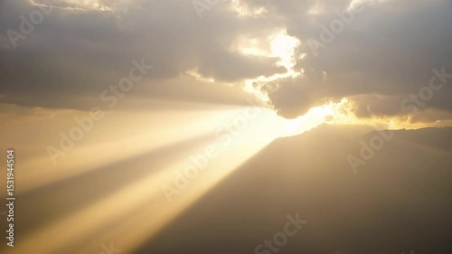 Sun Rays Streaming Through Clouds Over Mountain at Sunset