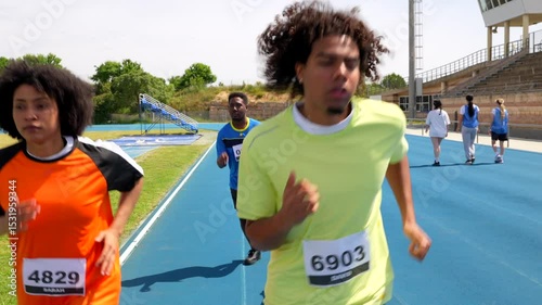 Athletes running on blue track in stadium