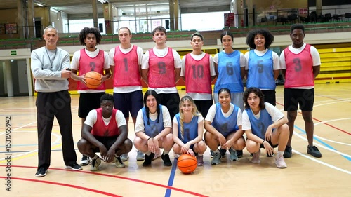 Basketball team posing with coach in gymnasium