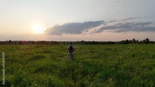 a man walking alone through a blooming field in the golden hour, enjoying the summer nature.