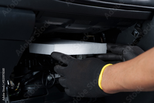 New cabin air filter being installed in a car.
Car air conditioning system maintenance and new filter installation.