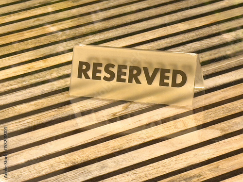 Reserved sign on wooden table with slatted pattern and glass reflection