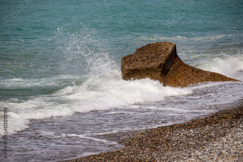 Fototapeta Naklejka Na Ścianę i Meble -  A large rock is in the ocean, and the water is crashing against it