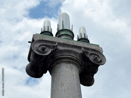 Historic stone column with decorative capitals against cloudy sky