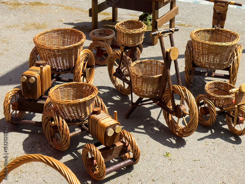 Handmade wicker bicycles and cars display on sunlit pavement