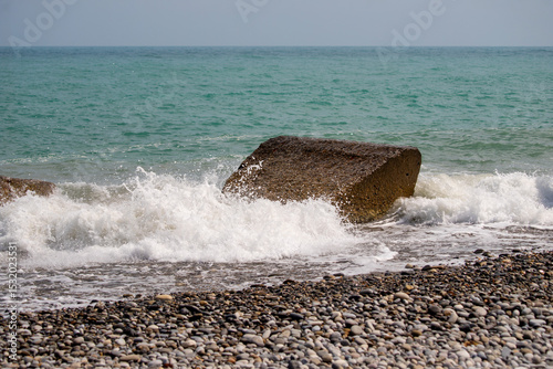 Fototapeta Naklejka Na Ścianę i Meble -  A large rock is in the ocean, and the water is crashing against it