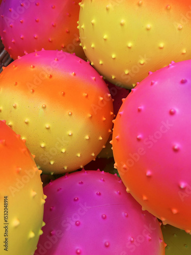 Colorful spiky rubber balls with gradient neon hues piled together in a close-up display