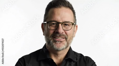 Man with glasses poses against bright white background wearing dark button down shirt
