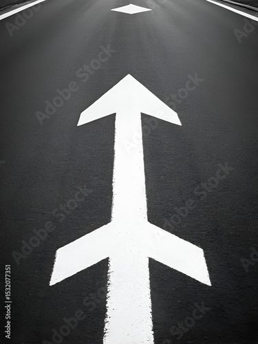 black and white photo of white arrow painted on pavement representing straight ahead or going forward symbol for forwardness achieving success or moving up arrow painted on road for traffic to proceed
