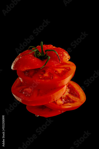 Juicy tomato cut into slices suspended in air with a kitchen knife. Fresh, dynamic concept of cooking and food preparation.