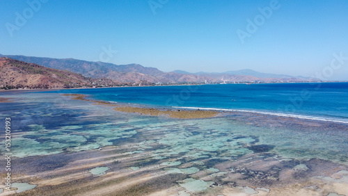 Scenic aerial view of ocean at low tide with patterned sand and coral reef in capital city Dili, Timor-Leste, Southeast Asia