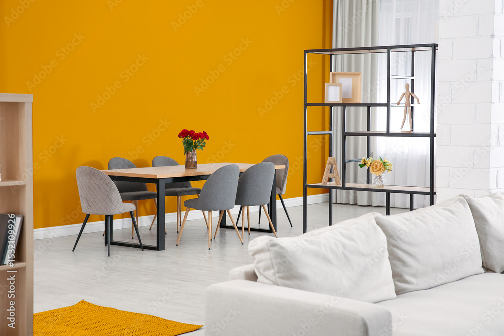 Fototapeta premium Dining table and chairs near orange wall in room. Interior design