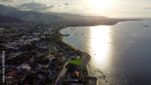 Scenic aerial drone view of capital city Dili, Timor-Leste in Southeast Asia with dusky golden sunlight over ocean