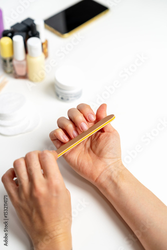 Woman doing nail care using nail file on white background