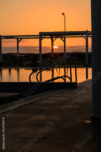 Still pool water reflecting dramatic sunset colors in a quiet residential complex on the Mediterranean island