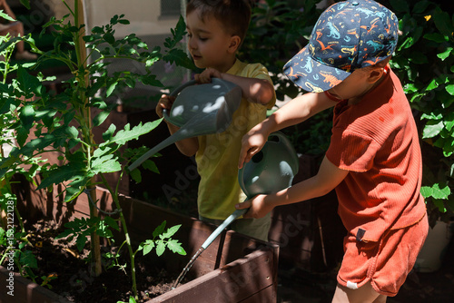 Foto Preschool children watering garden beds in summer camp