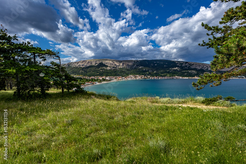 Fototapeta Naklejka Na Ścianę i Meble -  Green grass in a clearing, rest on a trail near the town of Baska, view of the bay and the city panorama